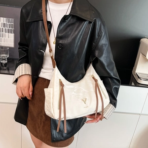 Sac bandoulière blanc plissé avec bandoulière en cuir marron et logo cerf doré sur modèle