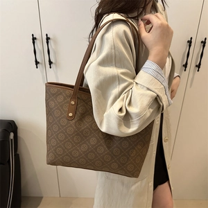 Retro brown tote bag with geometric print and leather straps worn by model in beige trench coat