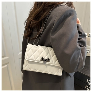 Gros plan d'un sac à bandoulière matelassé blanc avec chaîne et fermoir en V sur modèle