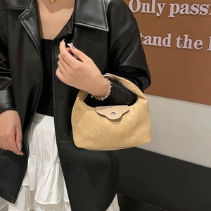Minimalist beige suede dumpling crossbody bag with silver buckle worn with leather jacket