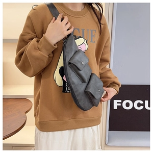 Detail view of dark grey multi-pocket chest bag showing vintage leather texture and buckle
