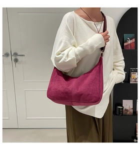 Detalle del bolso hobo de gamuza magenta suave con costuras decorativas y asa de cuero