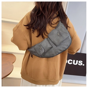 Detail of dark grey multi-pocket crossbody bag in soft faux leather on a model back