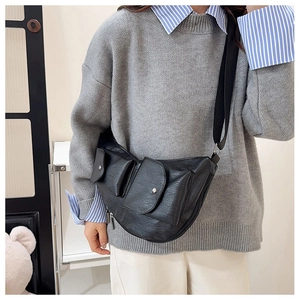 Detail of black semi-moon crossbody bag with pebbled leather and dual front utility pockets
