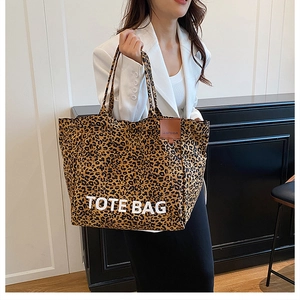 Close-up of leopard print tote bag on shoulder with white TOTE BAG text and leather label