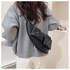 Detailed view of the black leather textured multi-pocket crossbody chest bag on model