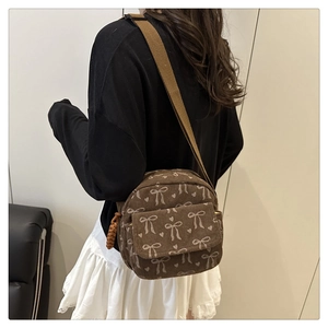 Brown corduroy crossbody bag featuring white bow patterns and heart prints