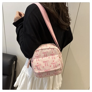 Detail of pink corduroy crossbody bag with cute bow patterns and heart prints
