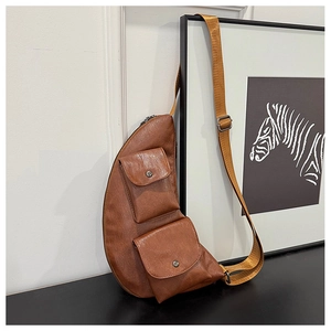 Detail of a brown faux leather chest bag with dual snap pockets and adjustable strap