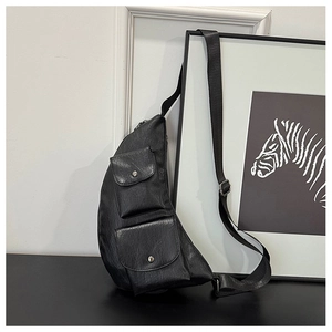 Detail of black faux leather chest bag showing soft crinkled texture and dual front pockets