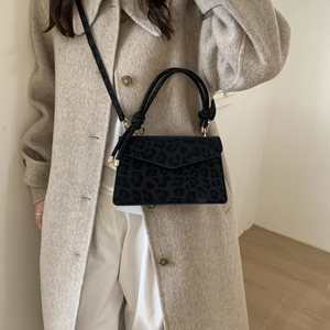 Elegant leopard print handbag with knot handle and shoulder strap worn with wool coat