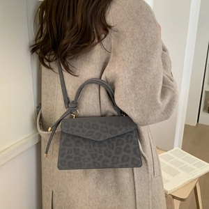 Retro grey leopard print handbag with golden hardware shown with a beige wool coat