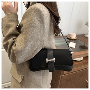 Detail einer schwarzen Baguette-Tasche aus Leder mit Silberschnalle und Schultergurt