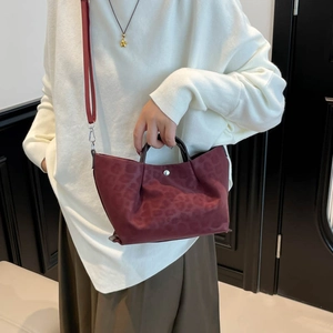 Burgundy leopard print tote bag with brown leather handles and a long shoulder strap