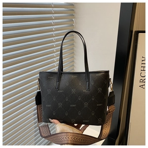 Close-up of black leather tote bag with embossed pattern and woven shoulder strap