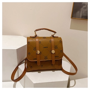 Close-up of brown textured leather mini backpack with cartoon rabbit and chick patterns