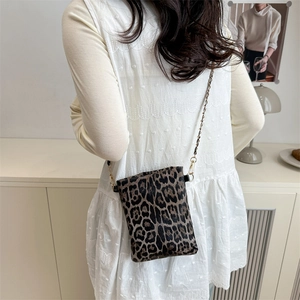 Fashionable leopard print crossbody bag with gold chain strap shown on a model