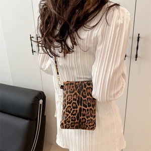 Fashionable leopard print crossbody bag with gold chain strap worn by a model