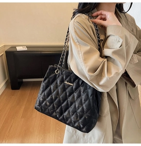 Detail of black quilted leather tote bag with elegant chain strap and large capacity