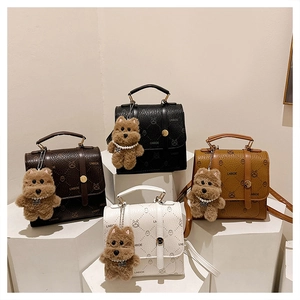 Detail view of four-color mini backpacks with letter patterns and plush bear charms