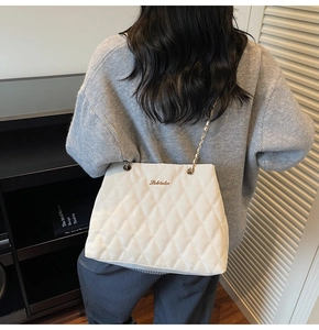 Detail of off-white quilted shoulder bag with gold metal chain and brand logo
