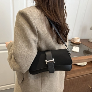 Minimalistische schwarze Schultertasche mit Silberschnalle in gemütlicher Wohnatmosphäre