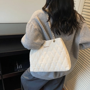 Chic white quilted leather shoulder bag with gold chain strap worn by a female model