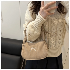 Gros plan du sac hobo en velours côtelé marron clair avec broderie nœud blanc