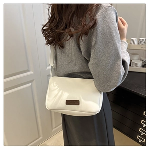 Détail d'un sac bandoulière blanc en nylon avec étiquette fashion sur un mannequin