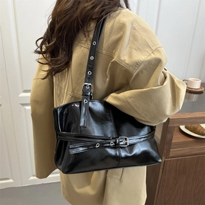 Sac fourre-tout noir brillant avec boucle métallique présenté dans un décor intérieur
