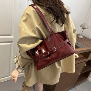 Sac porté épaule brillant bordeaux avec boucle, porté par un mannequin en intérieur