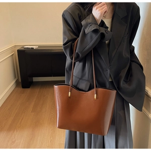 Brown leather bucket tote bag styled as an underarm shoulder bag for workwear