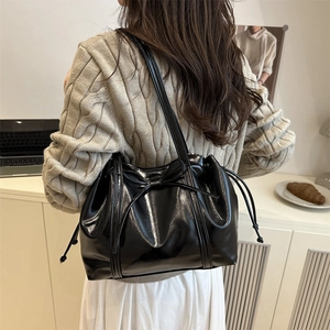 Glänzende schwarze Lackleder-Tote Bag mit Schleife und Kordelzug am Modell getragen
