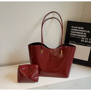 Detail of burgundy glossy tote bag with matching zipper pouch and gold hardware