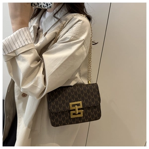Detail of vintage square crossbody bag with M-pattern and gold chain strap on model