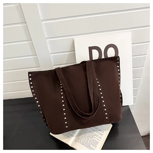 Détails des rivets argentés sur un grand sac cabas en daim marron chocolat au style rétro