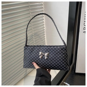 Detail of black patterned shoulder bag with a metallic silver butterfly clasp and handle