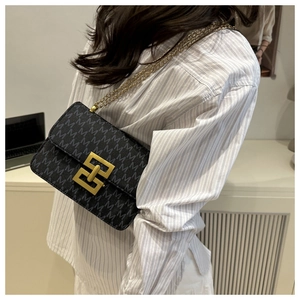 Detail of a vintage black monogram shoulder bag with gold chain strap on a model