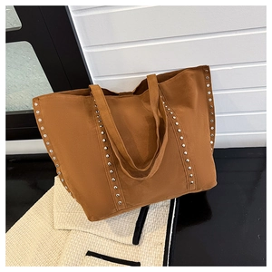 Gros plan d'un sac cabas en daim marron avec rivets métalliques et texture toile durable