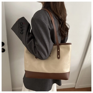 Model wearing a large PU leather tote bag in beige and brown for commuting style