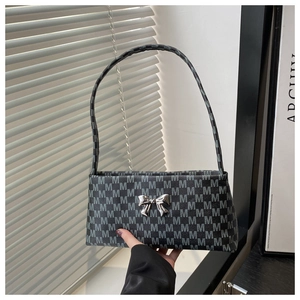 Close-up of a gray monogram shoulder bag featuring a metallic bow and sleek faux leather