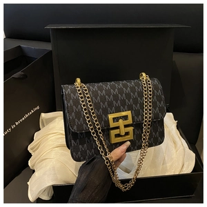 Détail du sac bandoulière à monogramme avec boucle dorée dans sa boîte cadeau