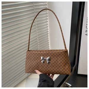 Close-up of brown monogram shoulder bag with a silver metallic bow and slim strap