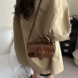 Brown vintage faux leather crossbody bag with top handle shown in a home setting