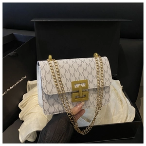 Détail du sac à chaîne en cuir blanc avec motif M dans un emballage cadeau de luxe