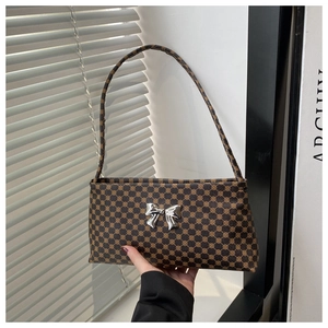 Close-up of vintage brown geometric pattern baguette bag with silver metal bow detail