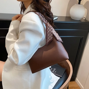 Sac à épaule en cuir grainé marron foncé avec foulard décoratif porté par un mannequin