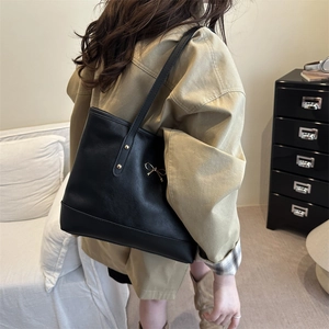 Minimalist black PU leather tote bag with gold bow ornament and long shoulder straps