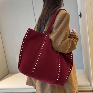 Grand sac cabas en daim bordeaux avec clous argentés porté par un mannequin