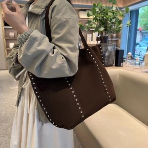 Grand sac cabas en daim marron chocolat avec rivets argentés porté par un mannequin